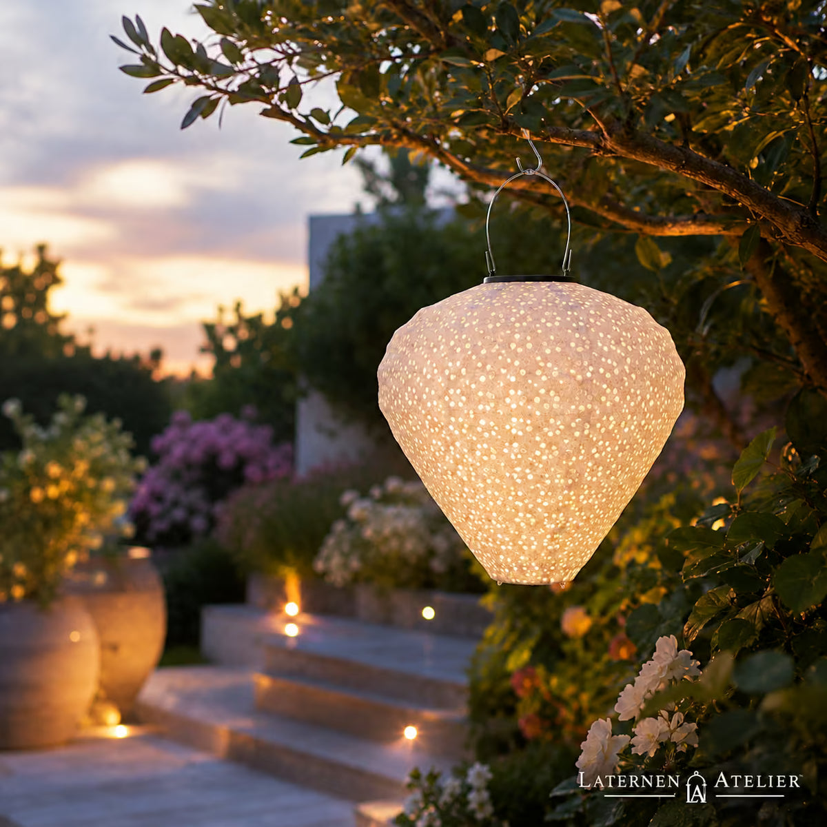 Solar-Lampion mit weißem Punktmuster in Tropfenform, hängend im Garten in der Abenddämmerung