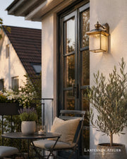 Kupfer-Wandlaterne mit Glasschirm und warmem Licht an einer Terrassenwand