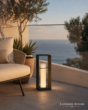 LED Solar Laterne aus Metall mit warmem Licht neben einer Outdoor-Lounge
