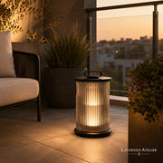 Schwarze Outdoor Solar-Laterne aus Edelstahl mit warmem Licht neben einer Outdoor-Lounge