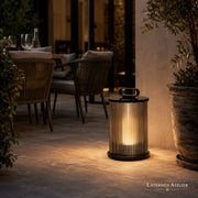 Schwarze Solar-Laterne Outdoor mit warmem Licht neben einem Esstisch auf der Terrasse