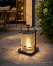 Solar-Gartenlaterne aus Edelstahl mit warmem Licht auf einer Terrasse neben Pflanzen