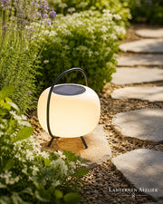 Solar-LED Laterne mit rundem Lichtkörper neben einem Gartenweg im Außenbereich
