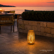 Solar-Rattanlaterne in heller Rattan-Optik mit warmem Licht auf einer Terrasse