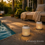 Weiße Solar-Laterne mit Lichtmuster auf einer Terrasse am Pool