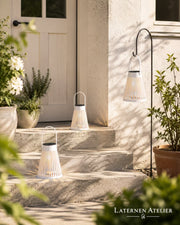 Weißes Solar-Windlicht mit warmem Licht auf Gartenstufen im Außenbereich