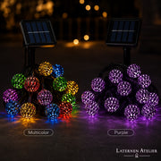 Bunte Solar-Lampion-Lichterkette an einer Pergola auf der Terrasse bei Sonnenuntergang