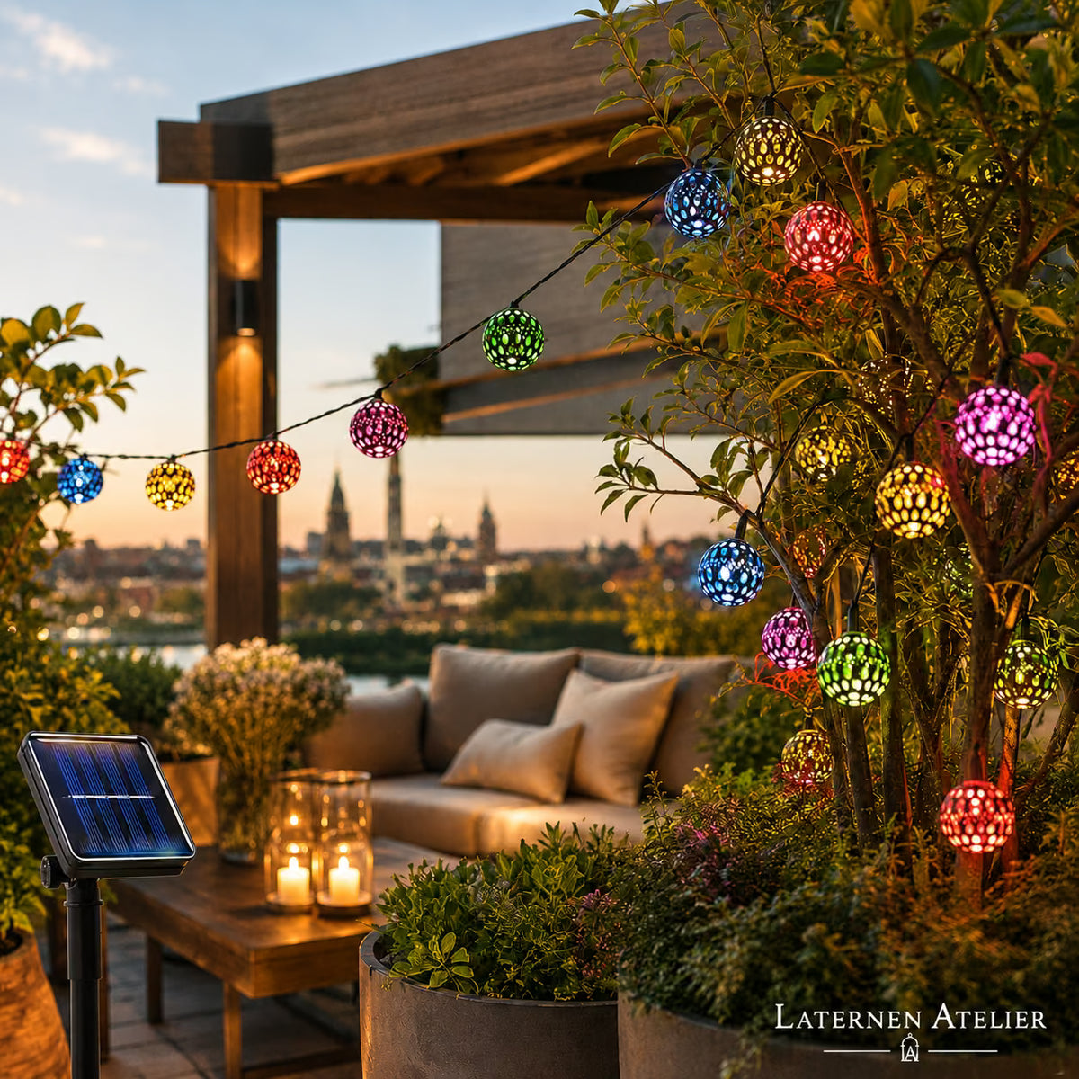 Bunte Solar-Lampion-Lichterkette beleuchtet eine Dachterrasse bei Nacht mit Stadtblick